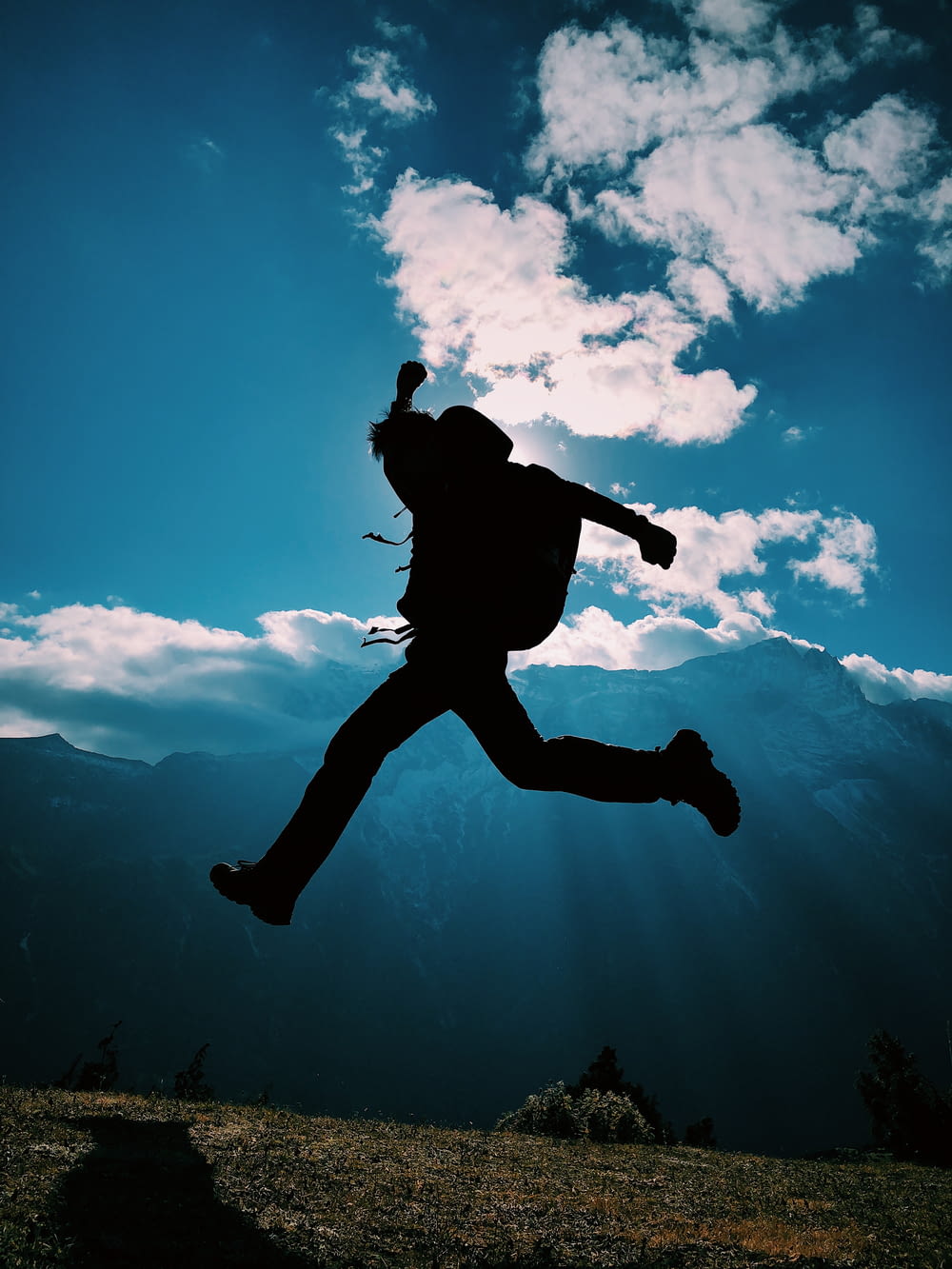 silhouette of person jumping on mountain
