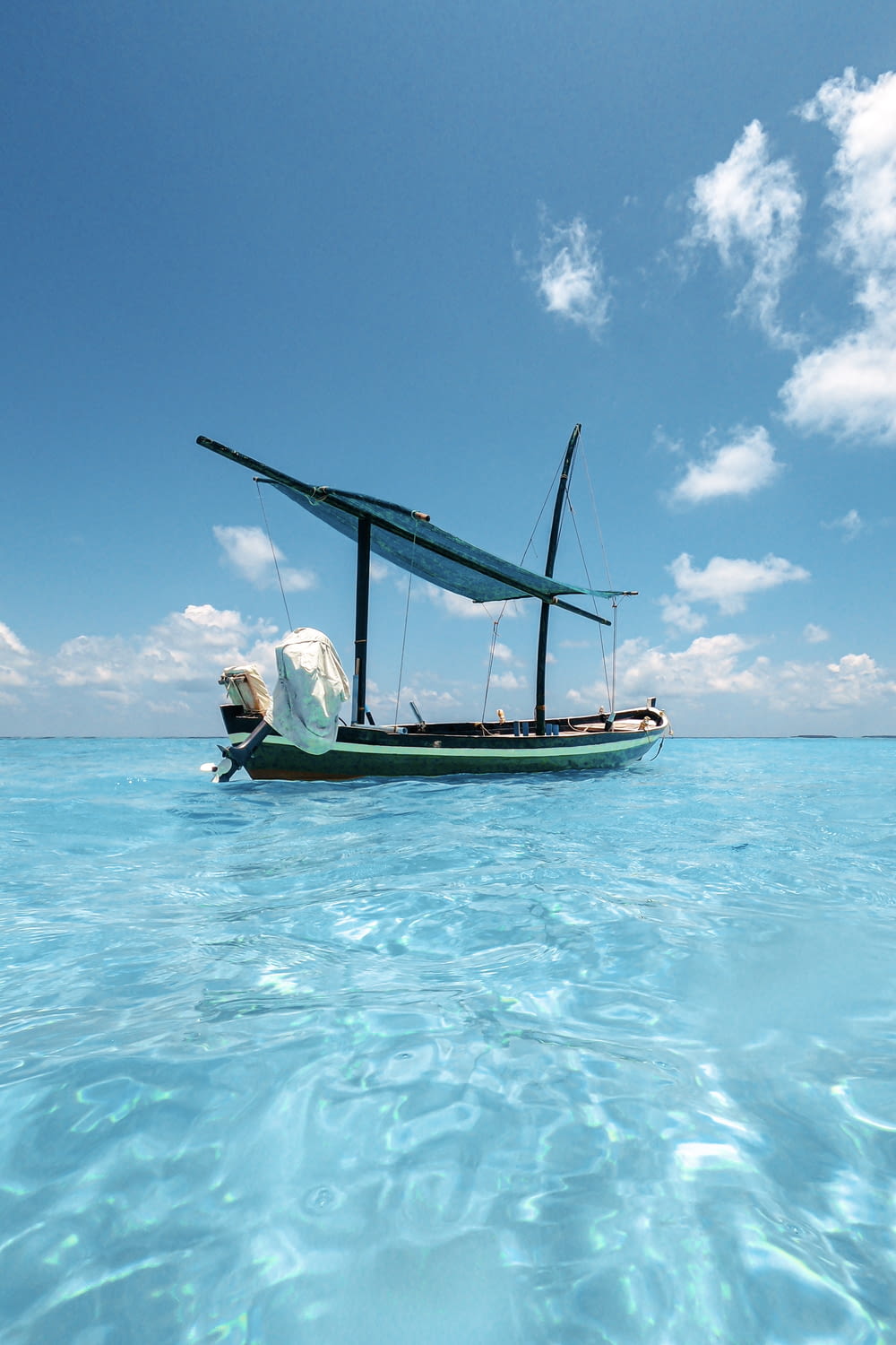 green and blue boat anchored at clear water sea