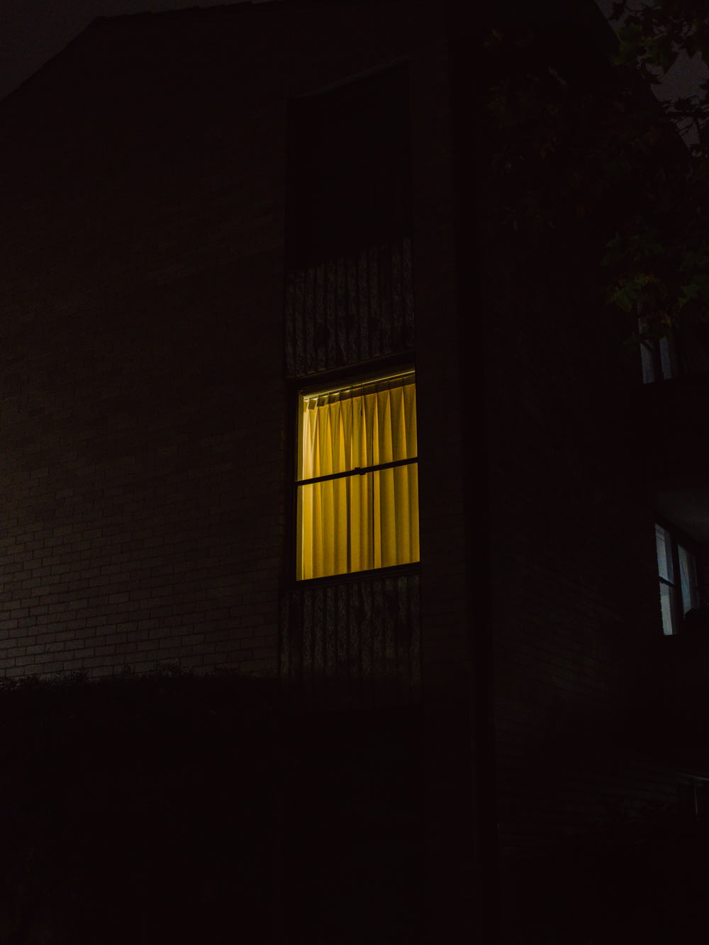a dark building with a window lit up at night