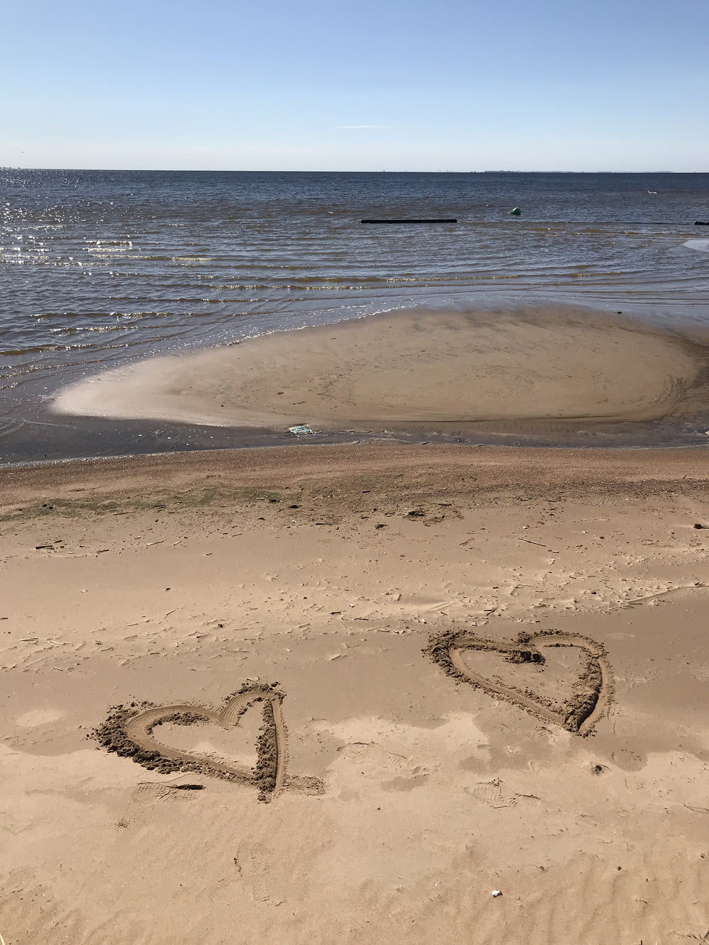 two hearts drawn in brown beach sand