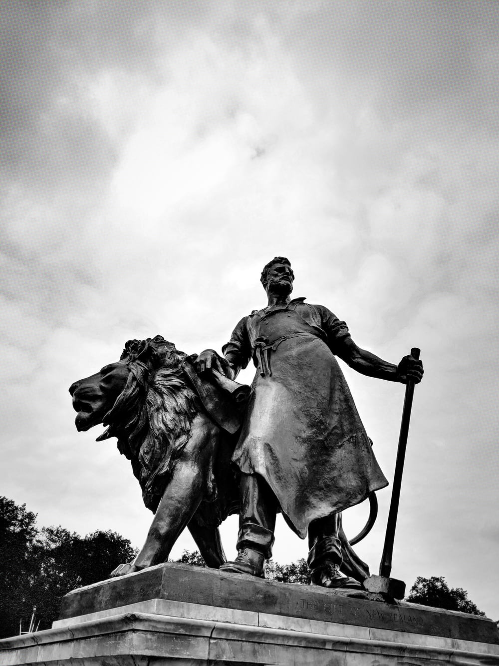 concrete man beside lion statue