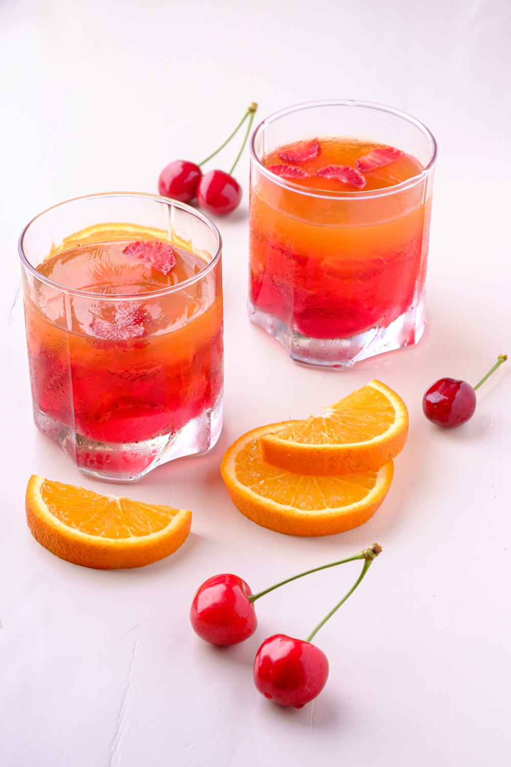 zwei Orangen- und Kirschgetränke in Gläsern
