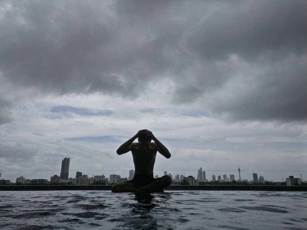 photography of man on body of water under cloudy sky during daytime