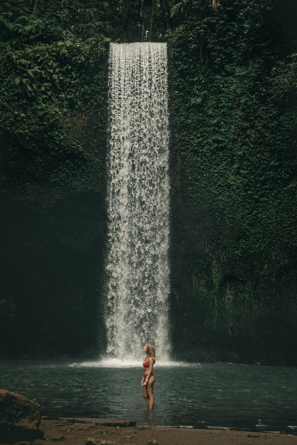 woman standing near waterfall during daytime