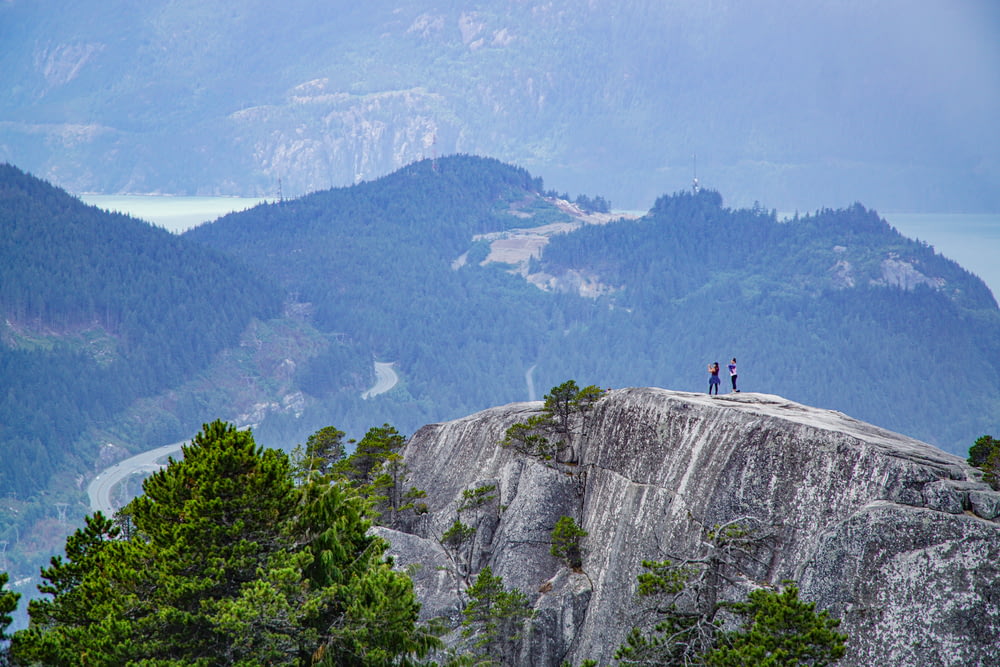 two people standing on top of rock mountain during daytime