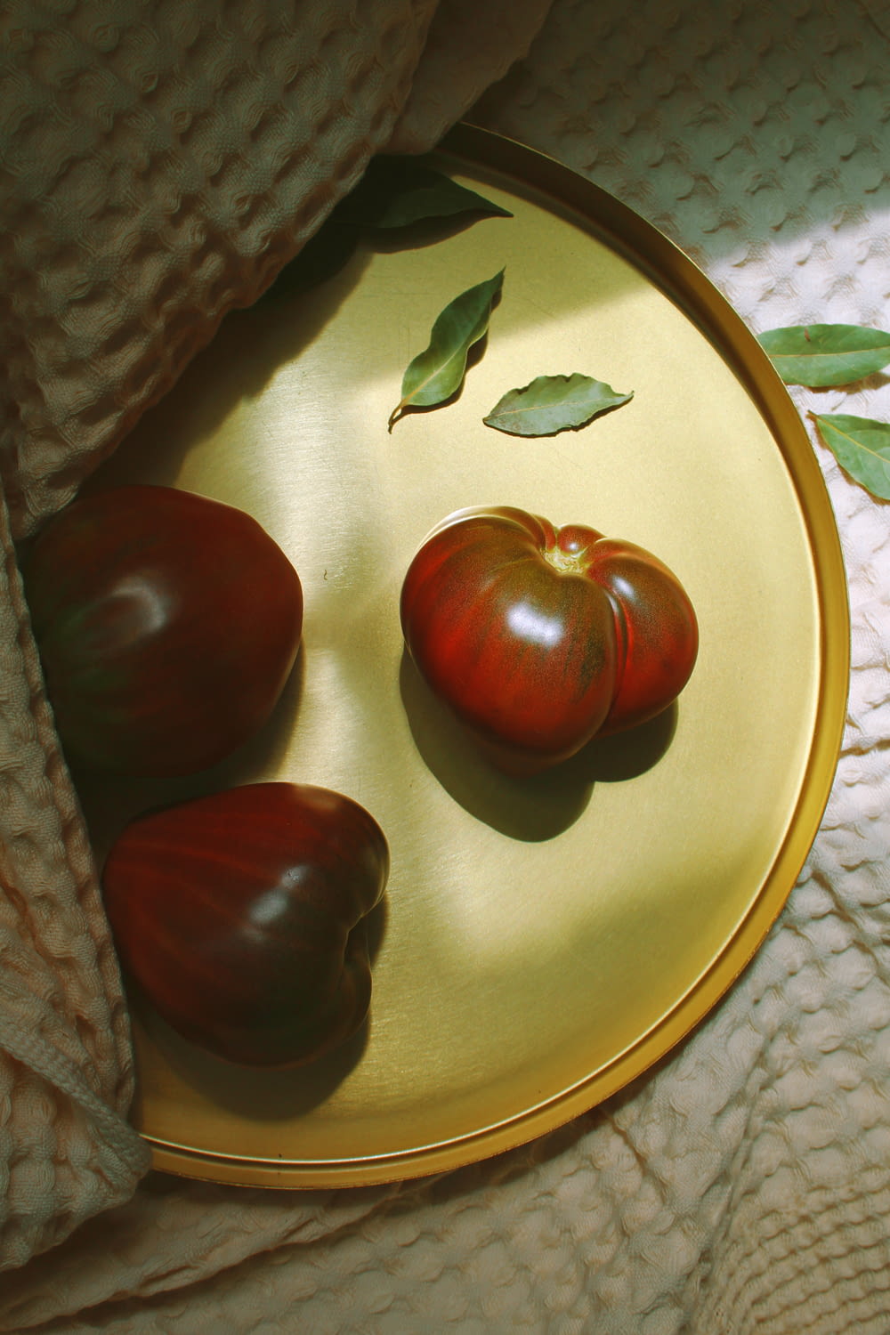 three red tomatoes on a gold tray