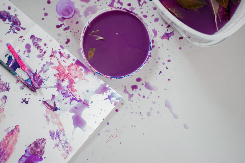 絵筆の横にある紫色の絵の具のカップ