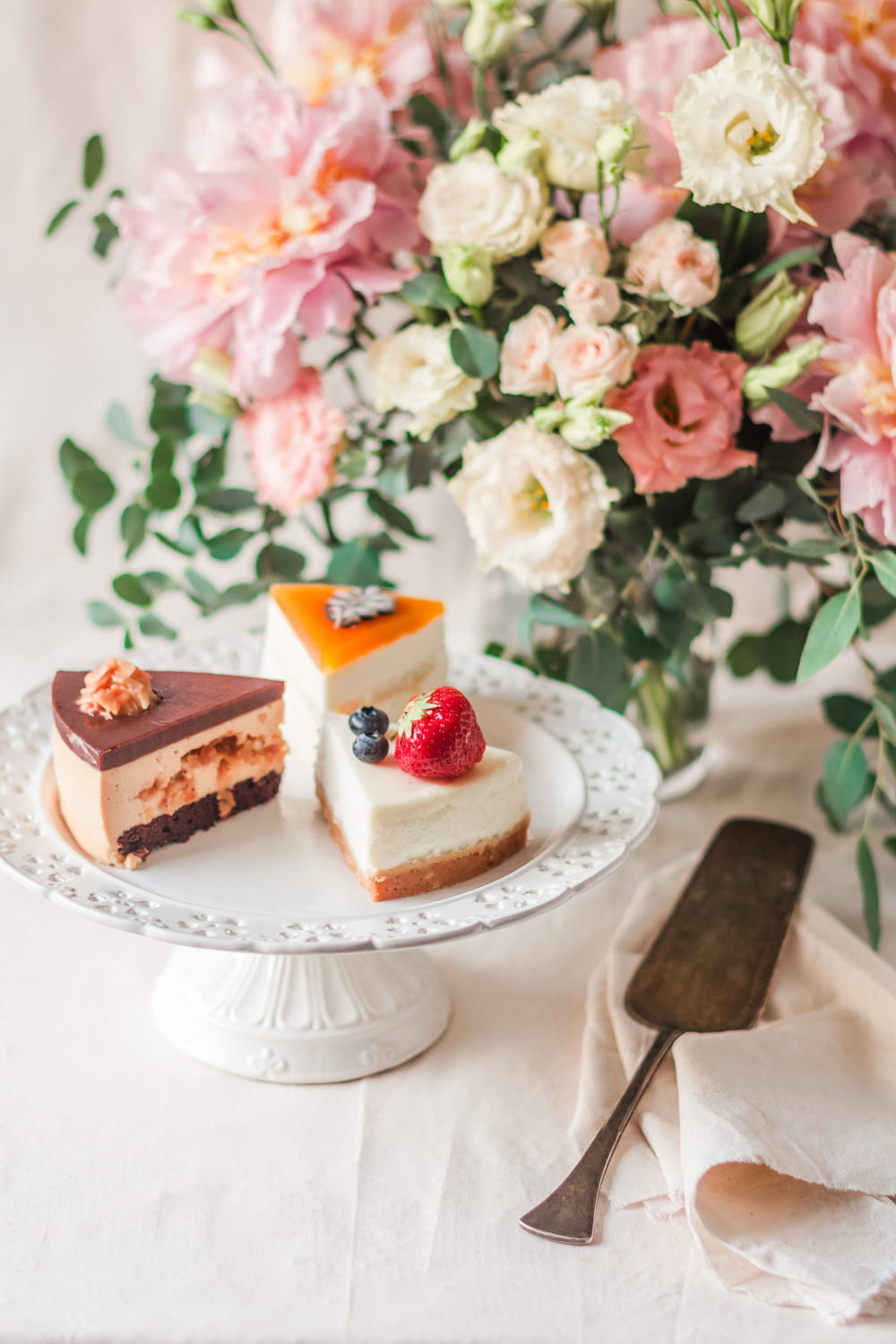 cake slices on cake stand beside cake server and flowers