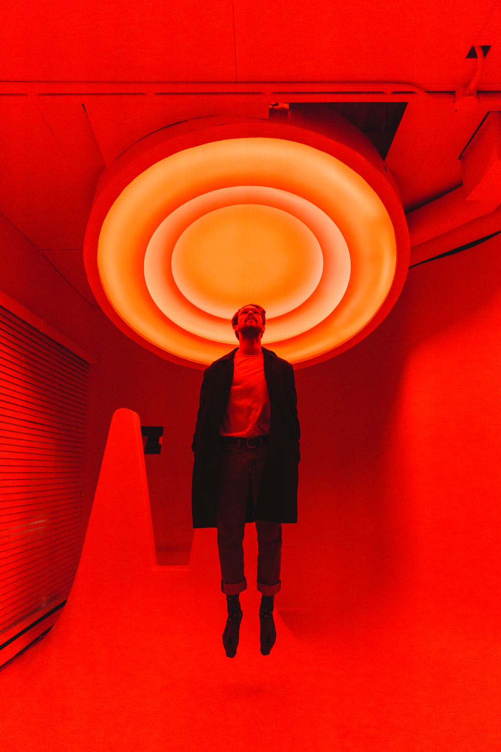 man standing under large red light inside room