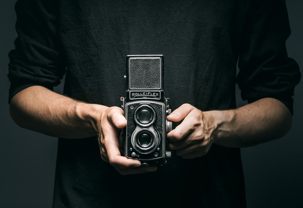 man holding vintage 2-lens camera