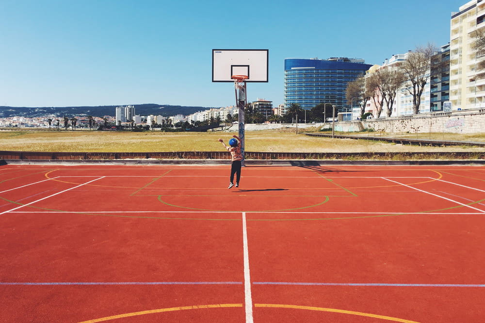 girl jumping near basketball court during daytime