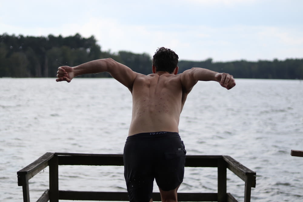 shallow focus photo of man in black shorts in front of body of water