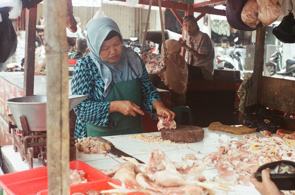 woman wearing green apron chopping meat