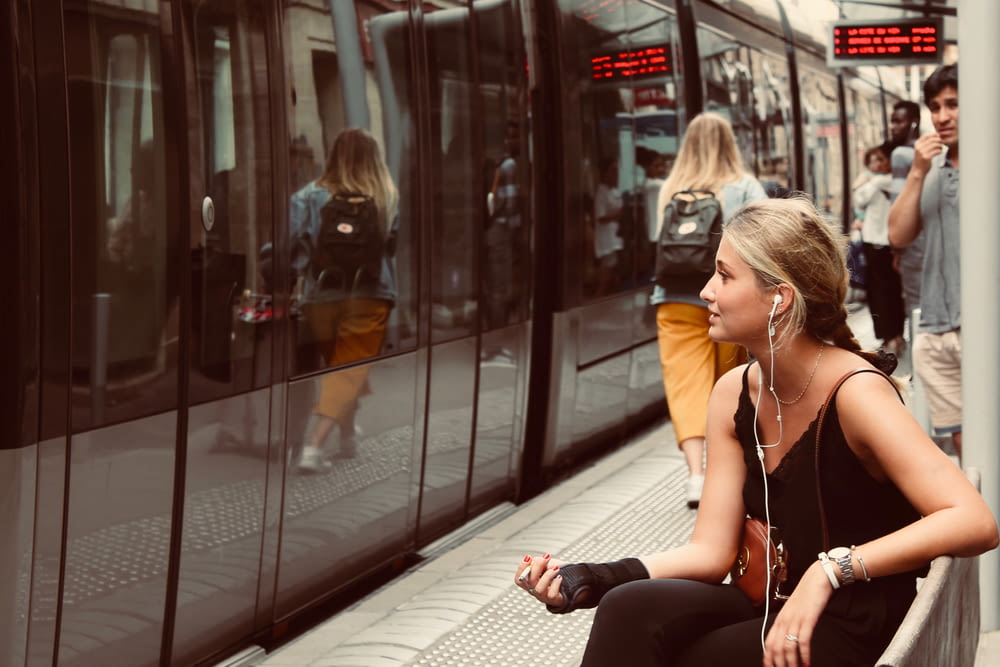 電車の前のベンチに座る女性