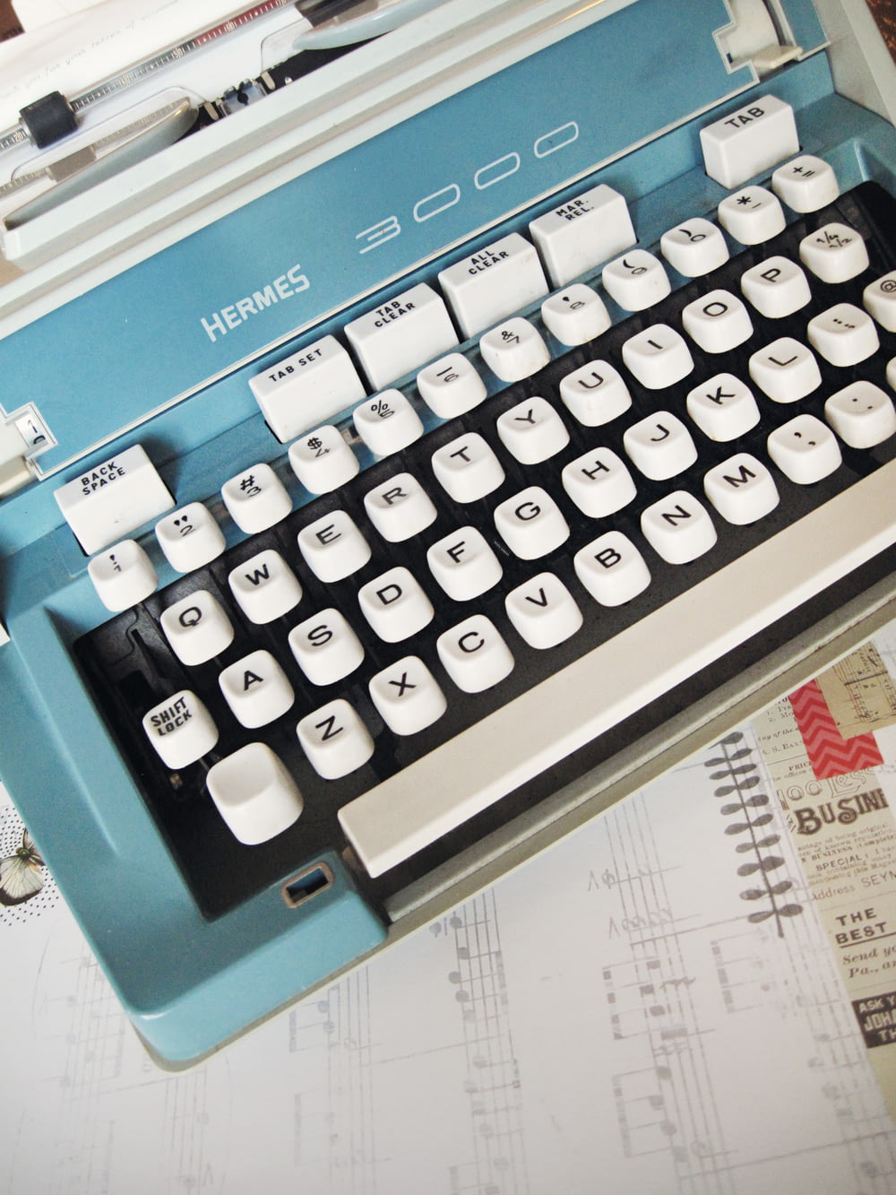 machine à écrire Hermes 3000 blanche et turquoise sur papier blanc