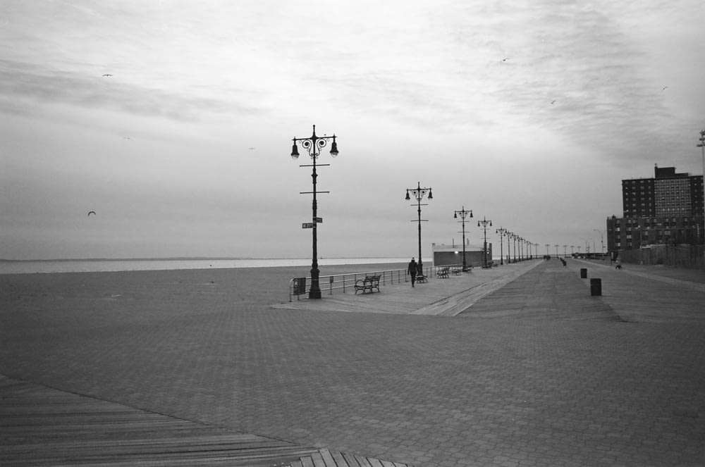 a black and white photo of a boardwalk next to the ocean