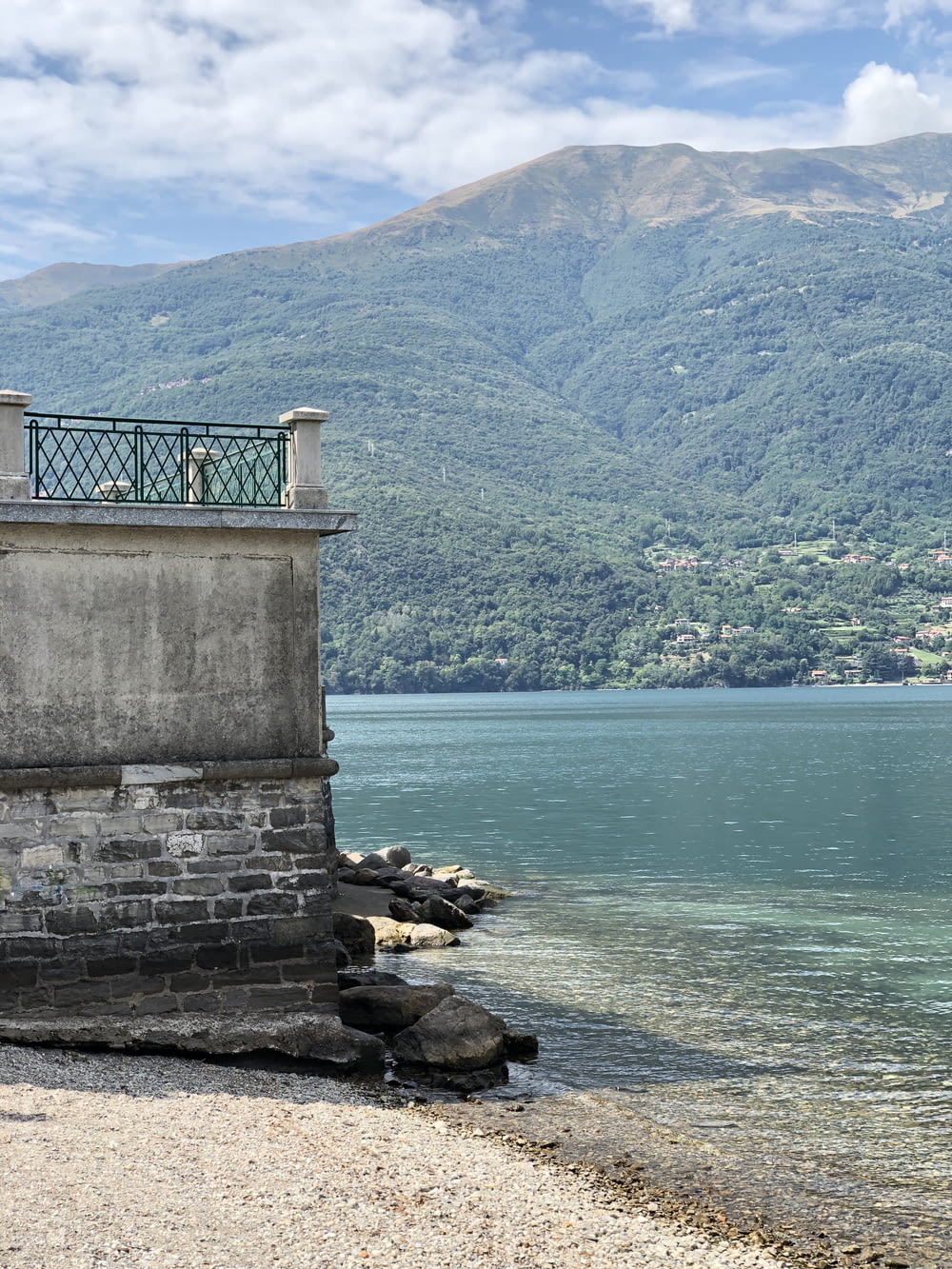 a clock tower sitting on top of a stone wall next to a body of water
