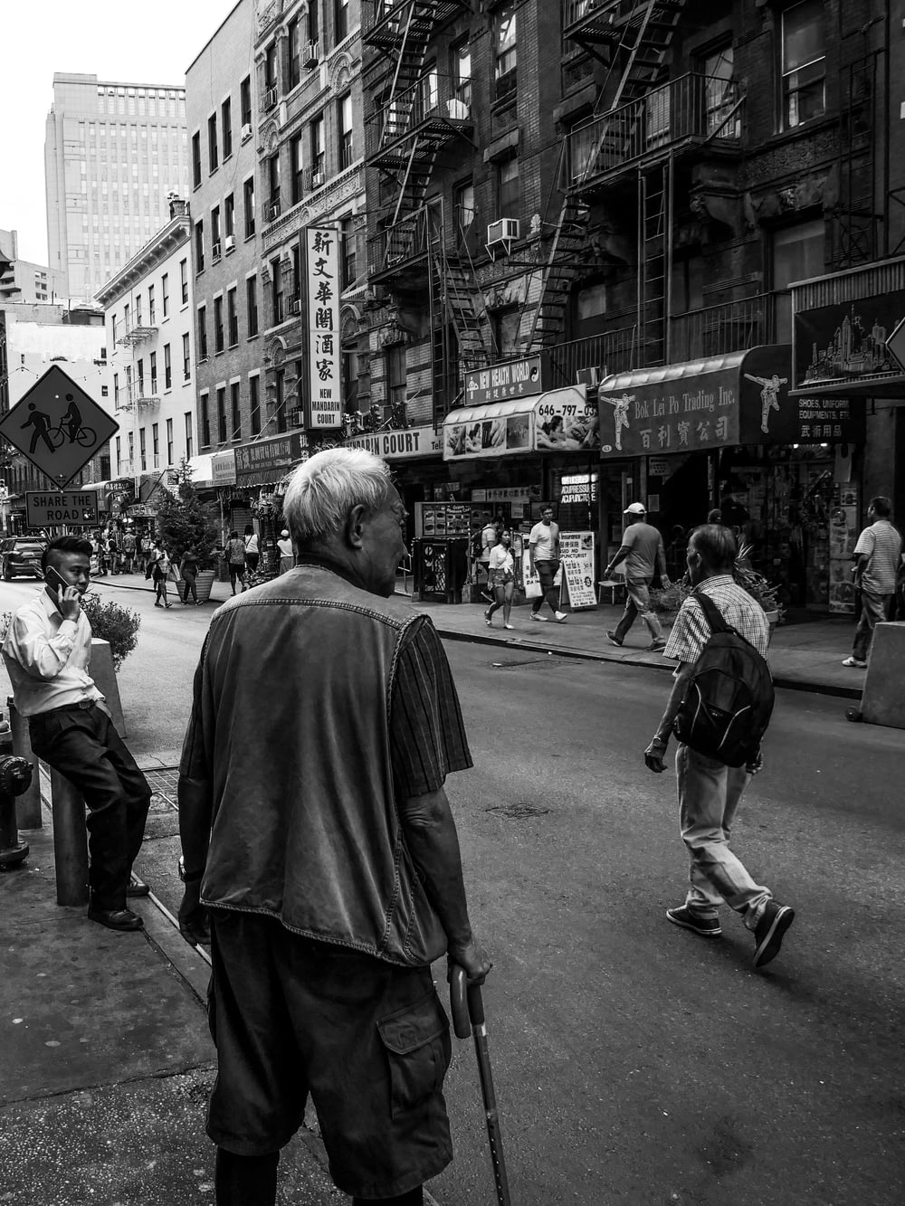 fotografia em tons de cinza de pessoas caminhando perto da rua