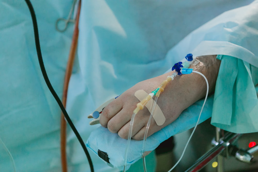 Una persona en una cama de hospital con una vía intravenosa