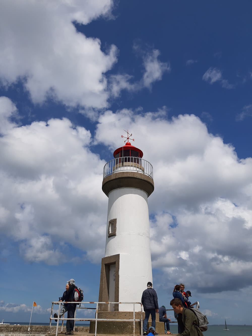 people besides white and gray lighthouse during daytime