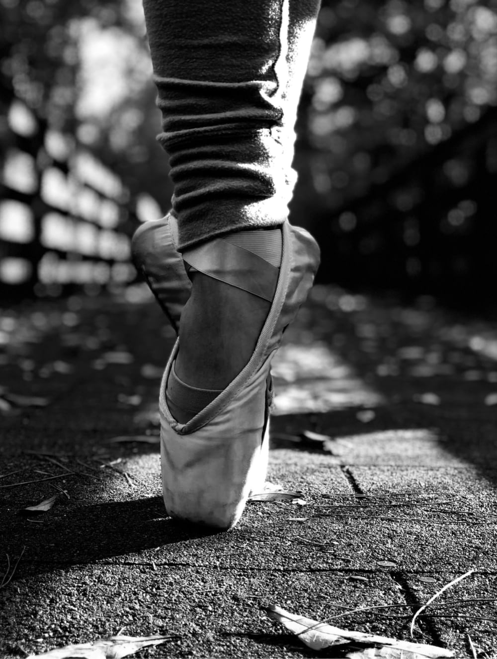 a black and white photo of a person wearing ballet shoes