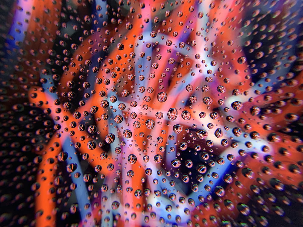 Wassertropfen auf Glasscheibe mit roten und blauen Lichtwellen