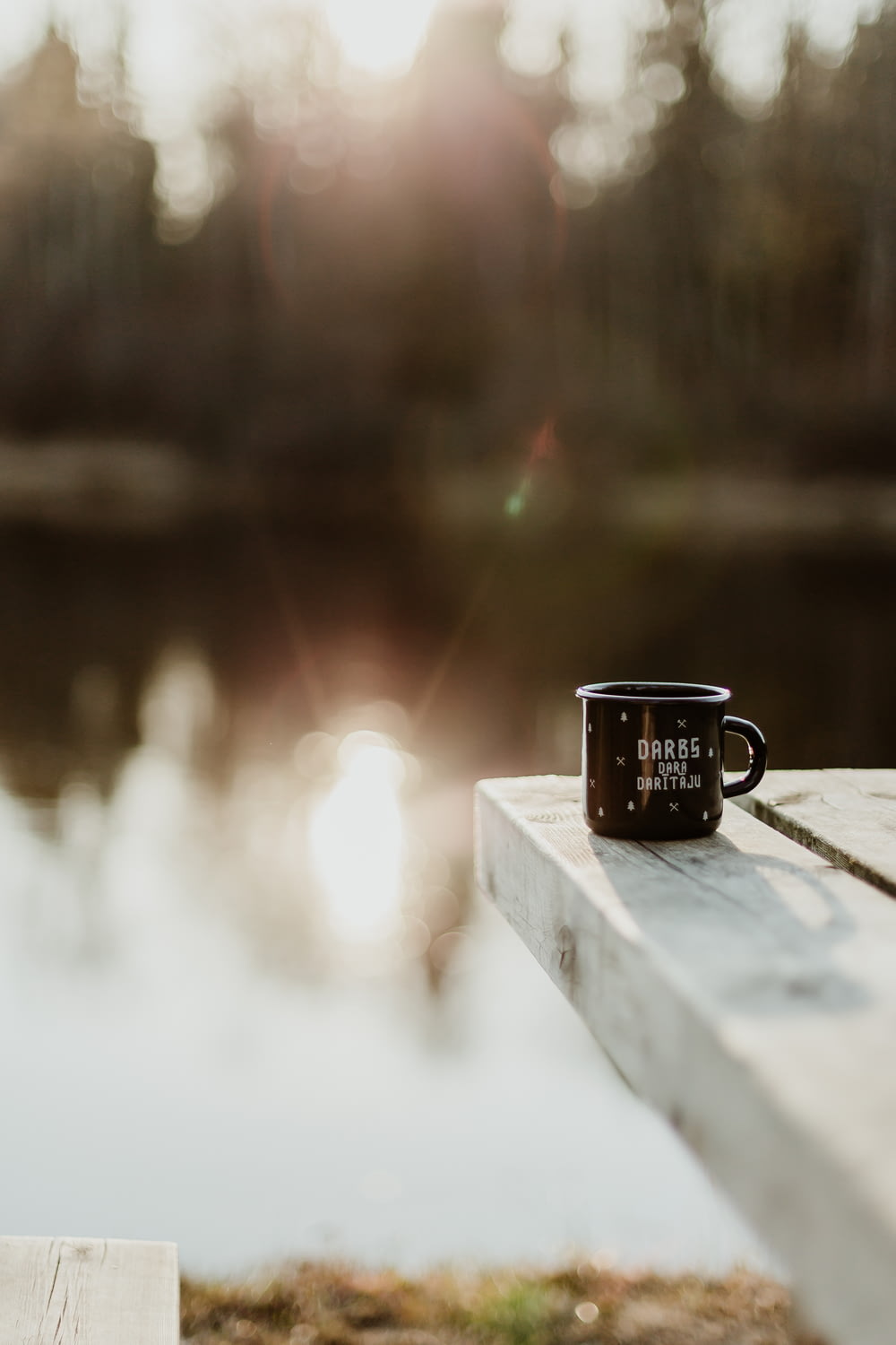 black mug on dock near lake