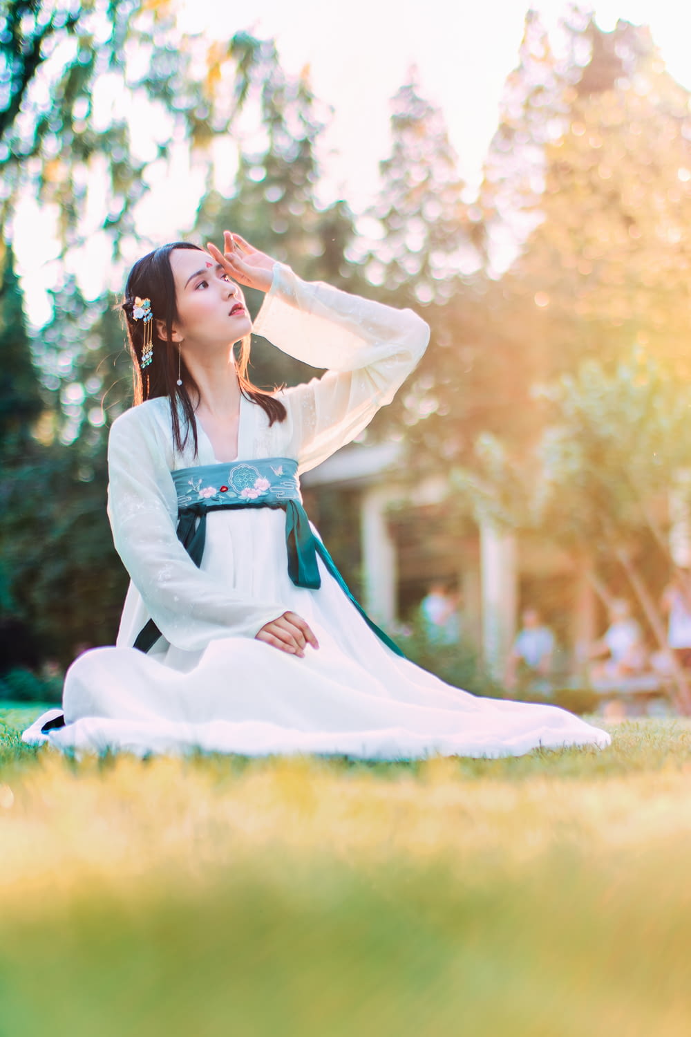 Femme portant un hakama blanc et bleu assise sur une prairie
