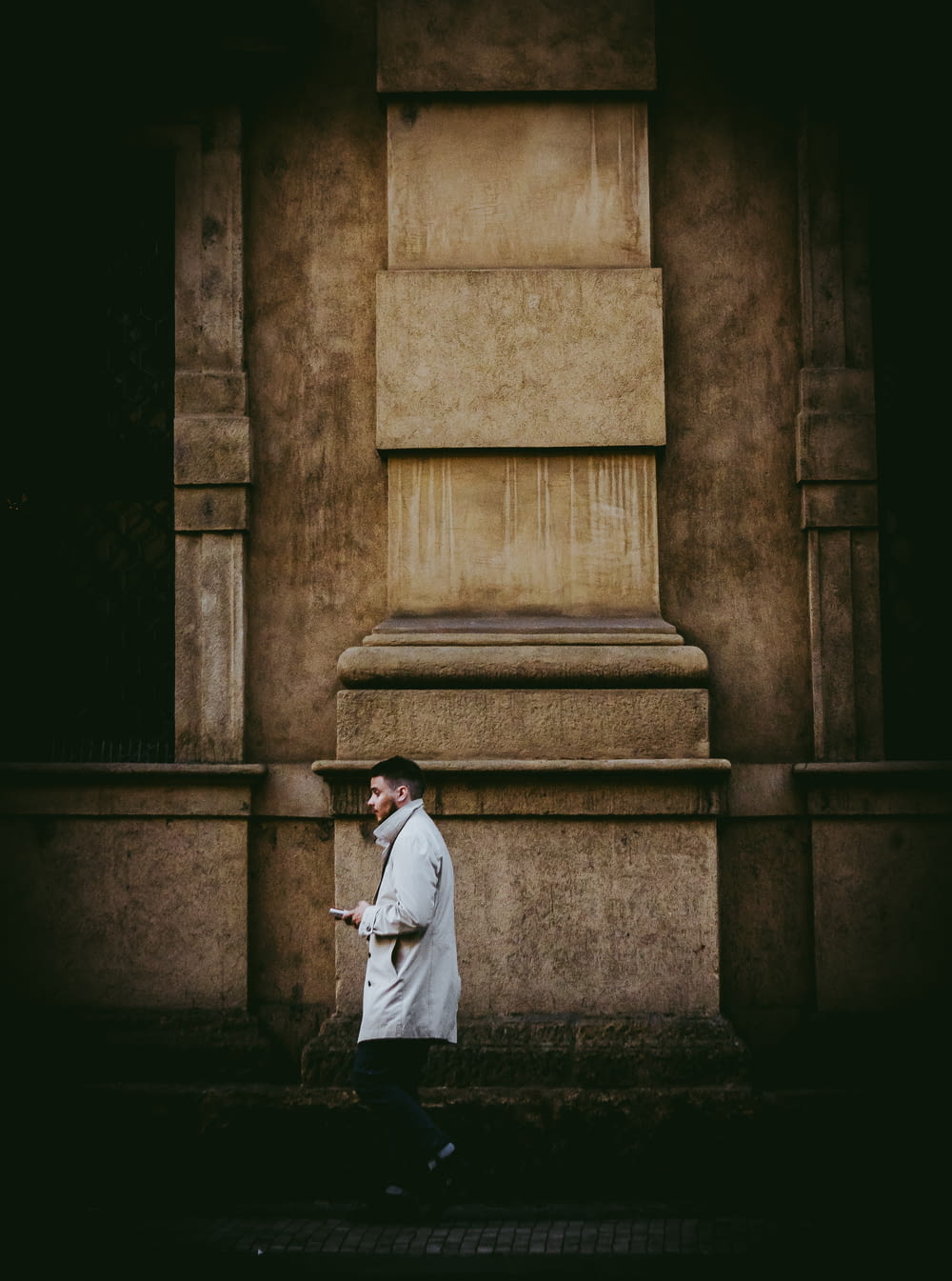 man in white coat walking beside wall