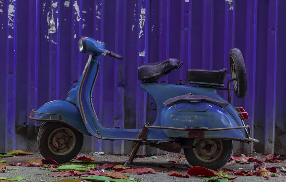 a blue scooter parked in front of a purple wall
