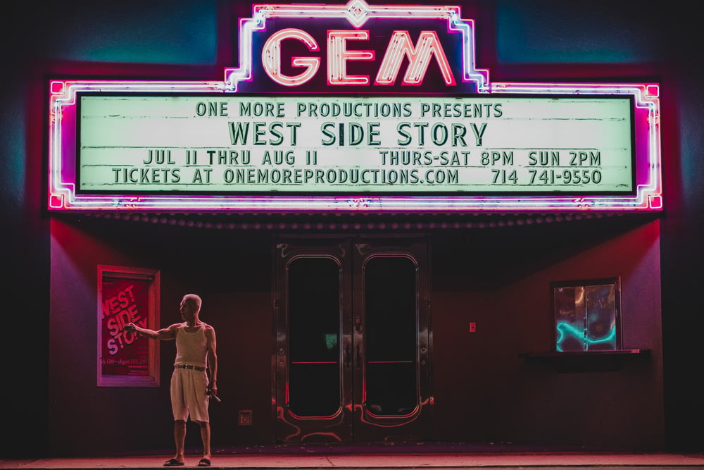 man standing in front GEM movie house