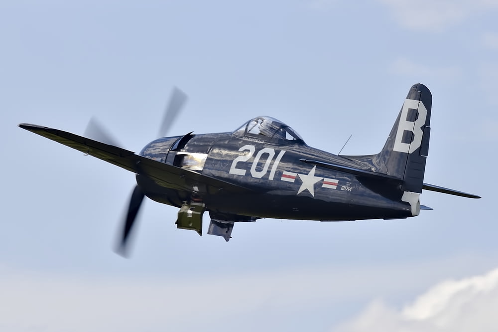 shallow focus photo of black monoplane flying during daytime