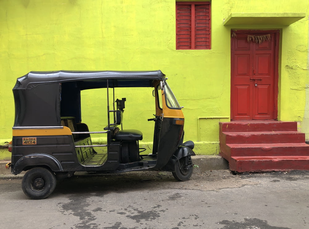 black and yellow vehicle near yellow wall and red door close-up photography