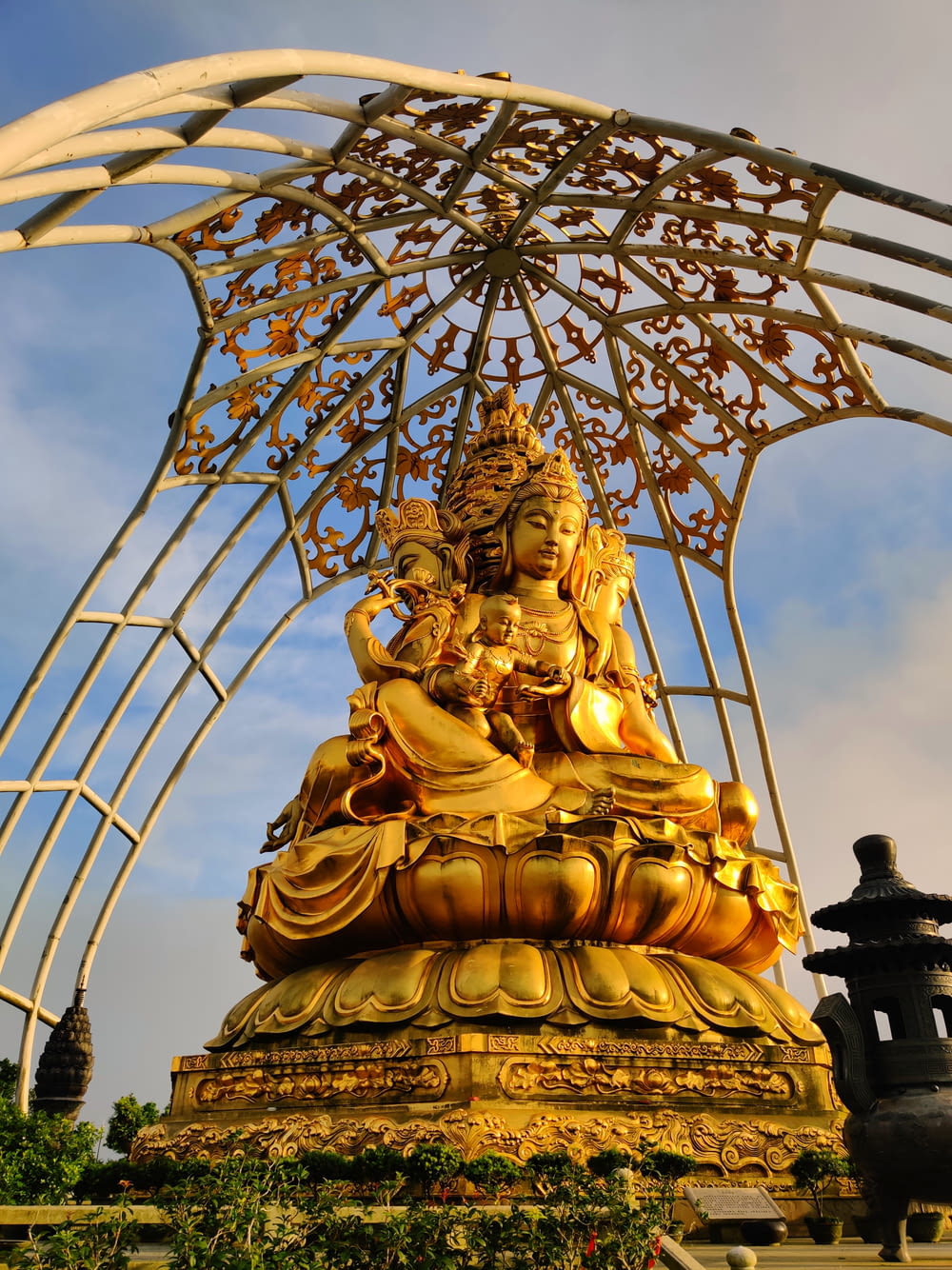 a golden buddha statue sitting under a metal structure