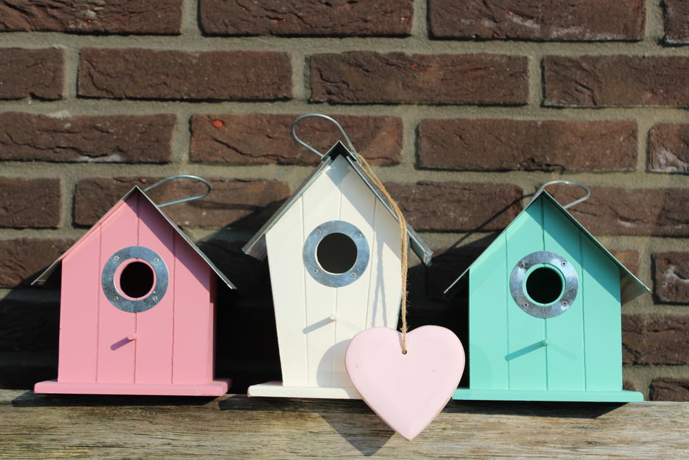 three wooden bird houses in assorted colors
