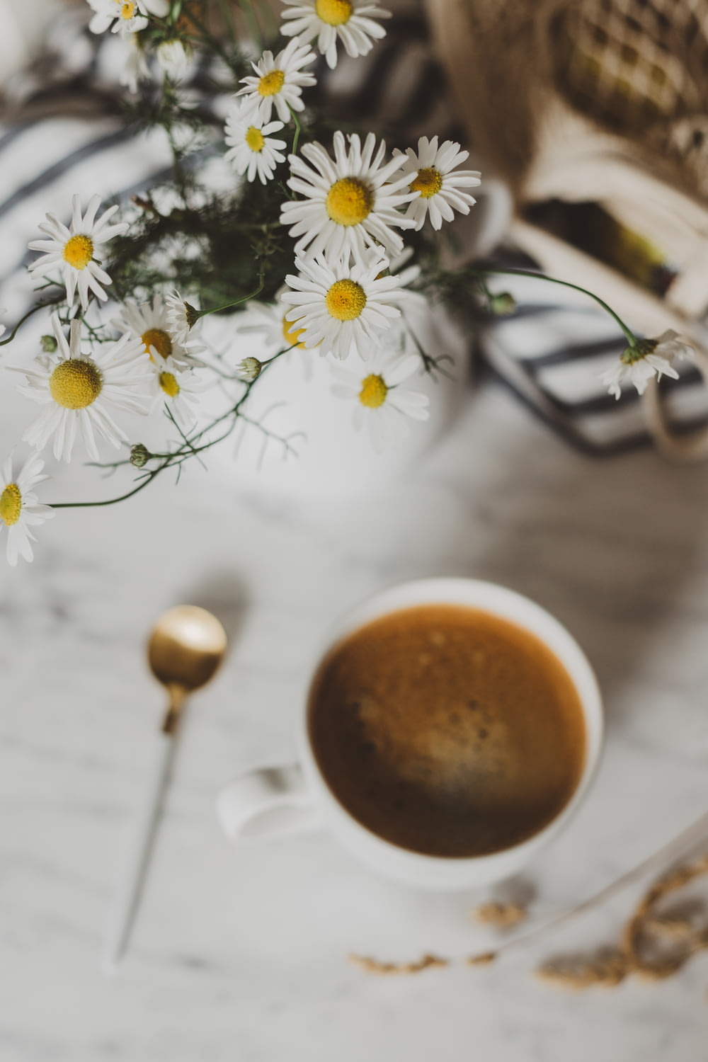 selective focus photography of white flower arrangement beside mug of coffee
