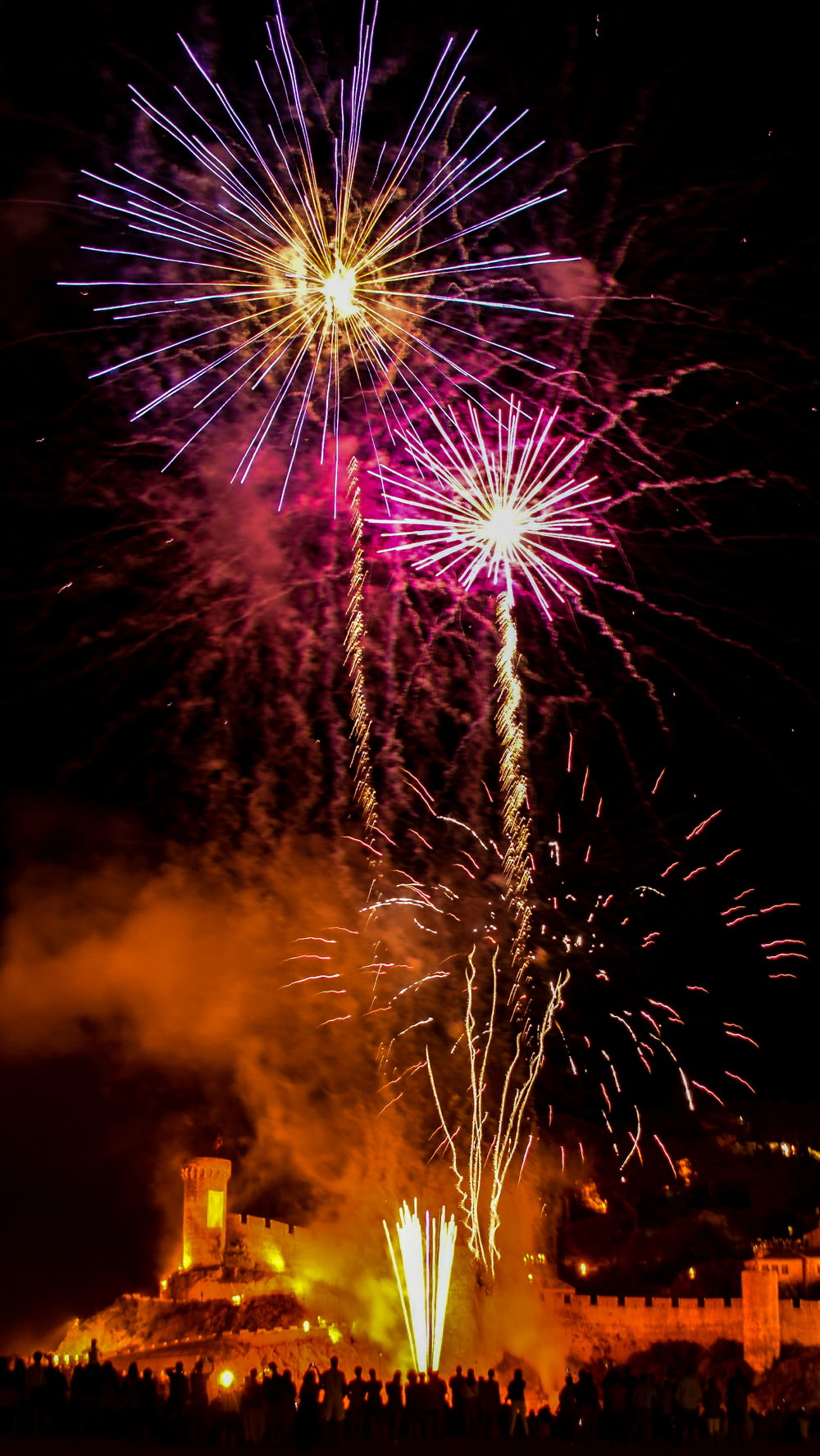a large fireworks display with a castle in the background
