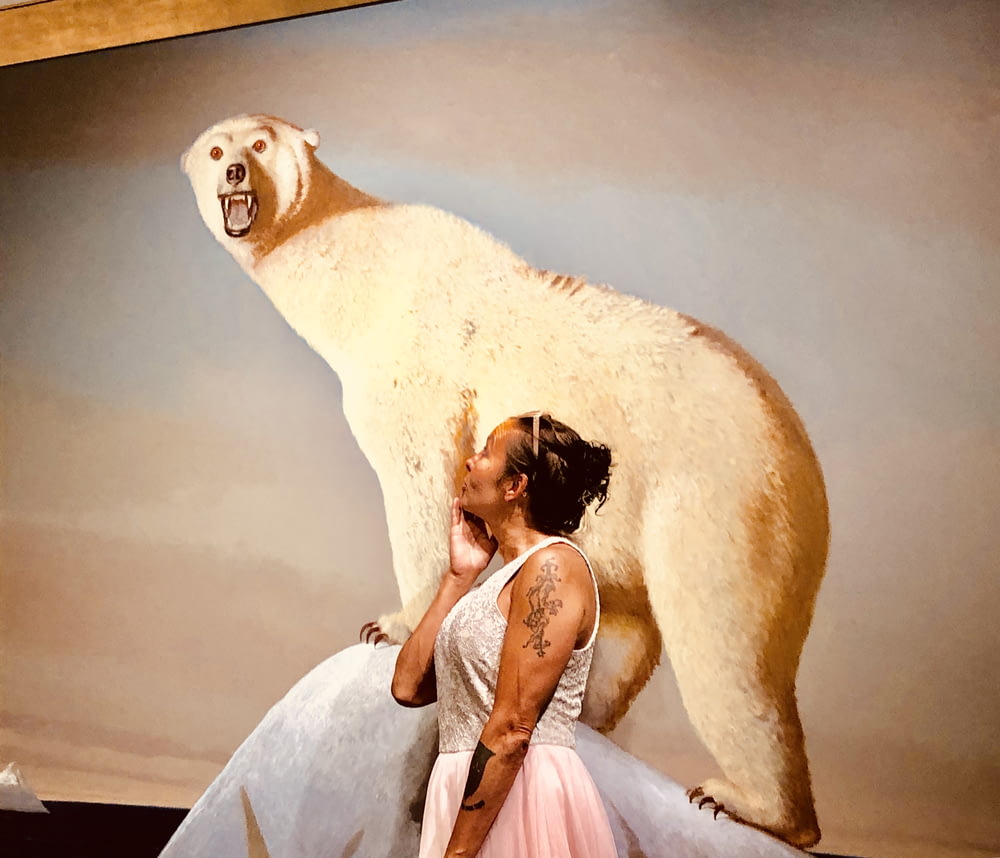 woman wearing white sleeveless dress besides photo of white polar bear