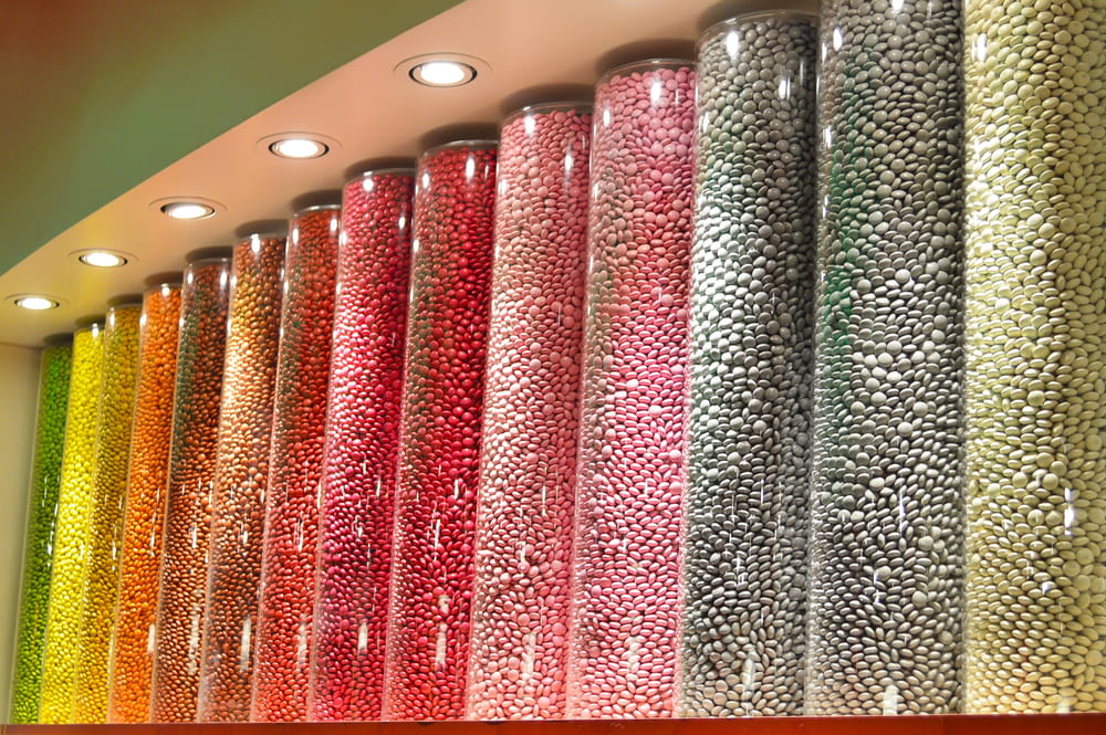 a row of glass vases filled with different colored candies