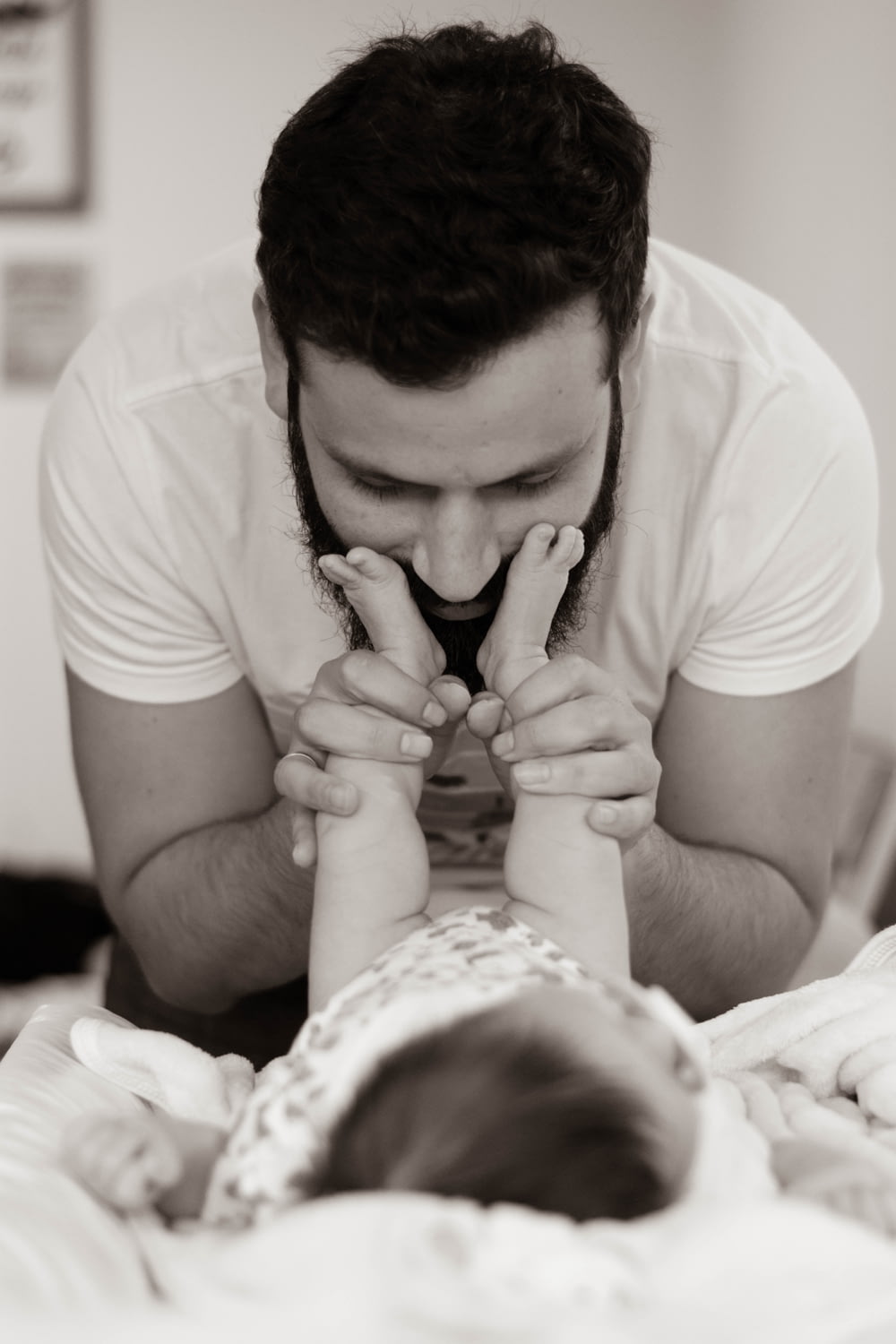 Graustufenfotografie eines Mannes, der mit Baby spielt