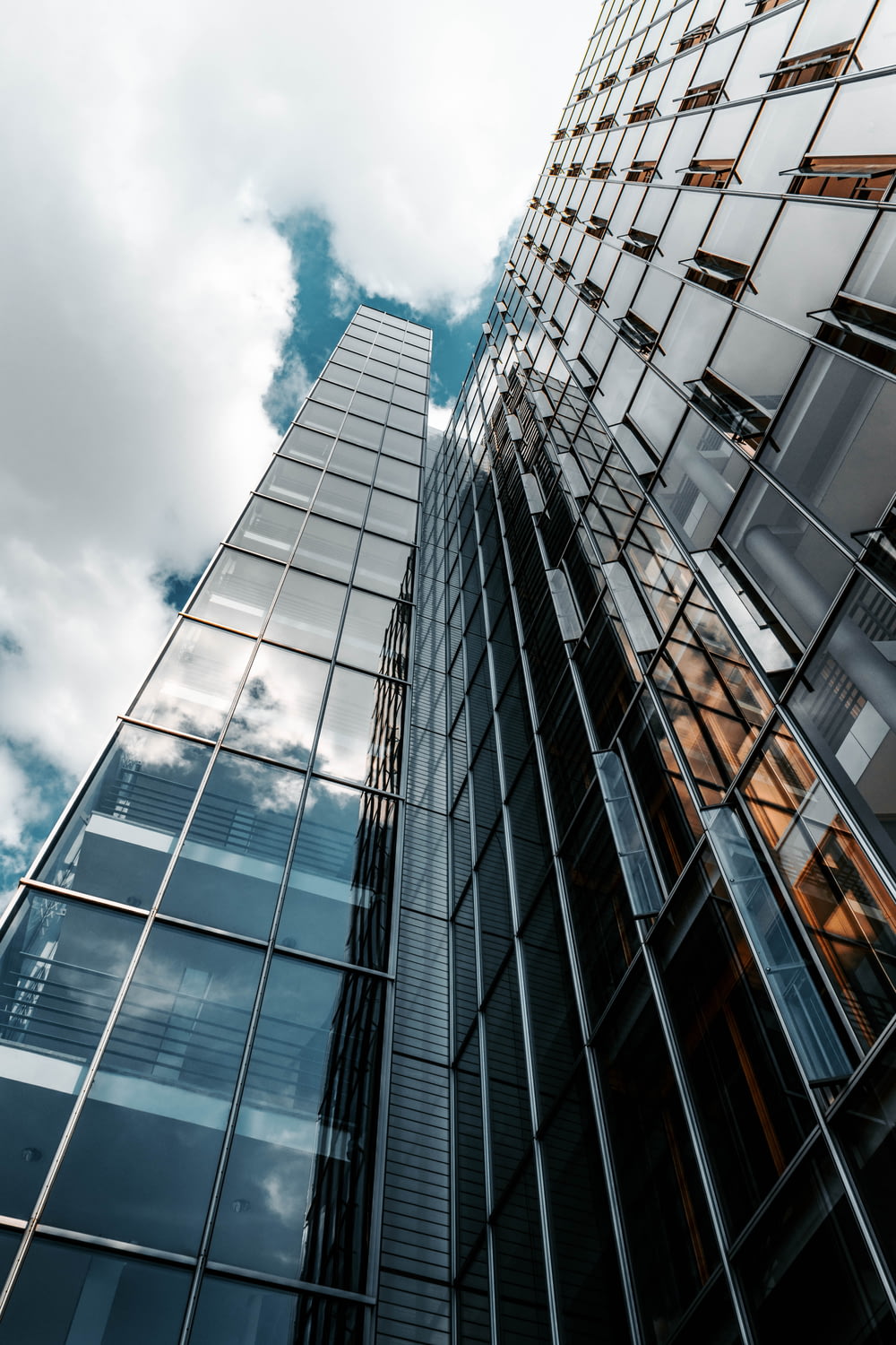 Photographie en contre-plongée d’un bâtiment en verre sous un ciel nuageux