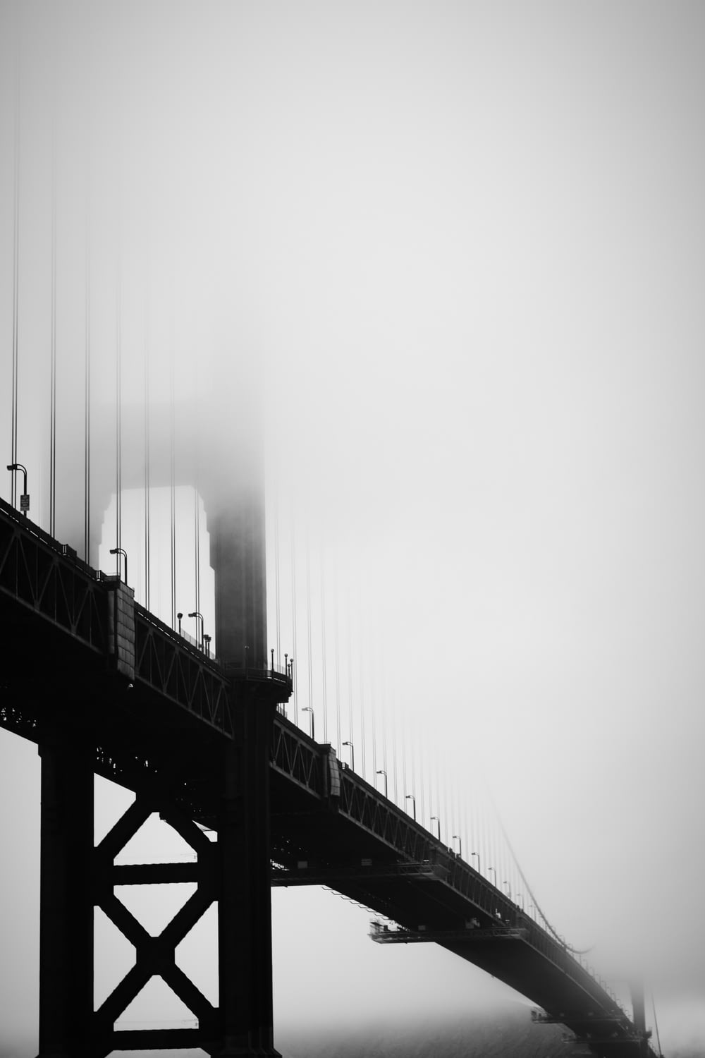 grayscale photography of bridge under fog
