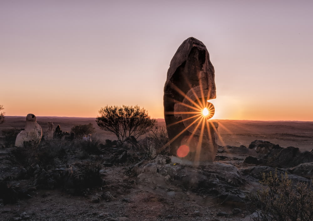 太陽は砂漠の大きな岩の後ろに沈んでいます