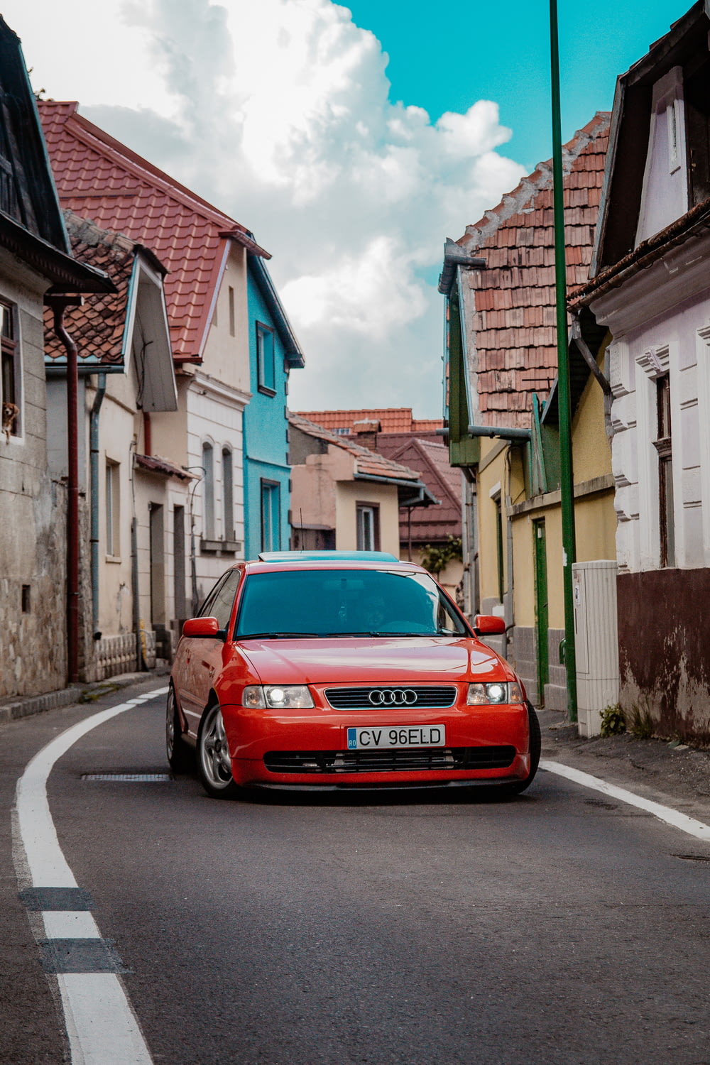 Audi RS2 vermelho na estrada perto das casas