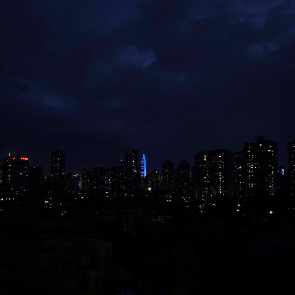 city lights turned on at night under cloudy sky