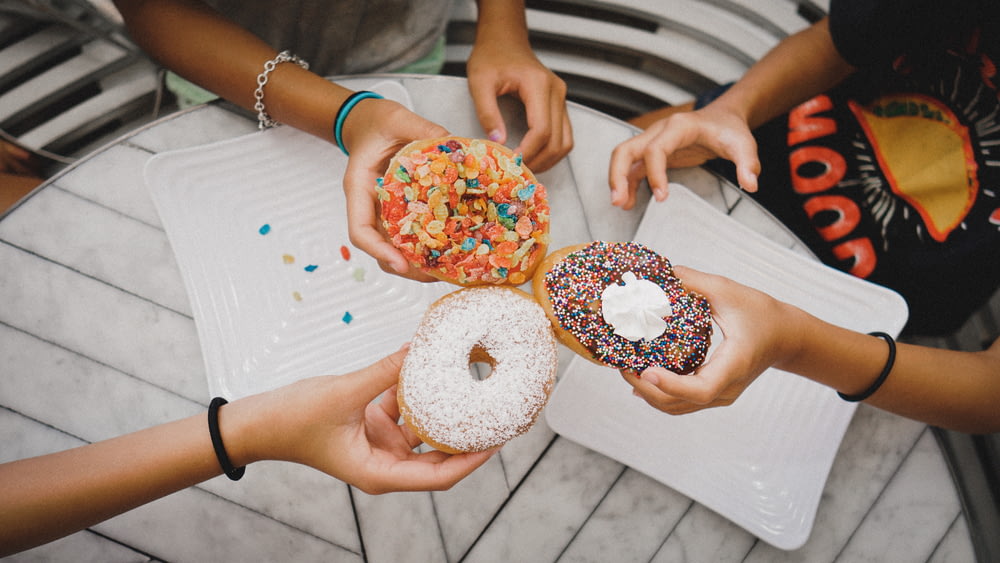 shallow focus photo of person holding donuts