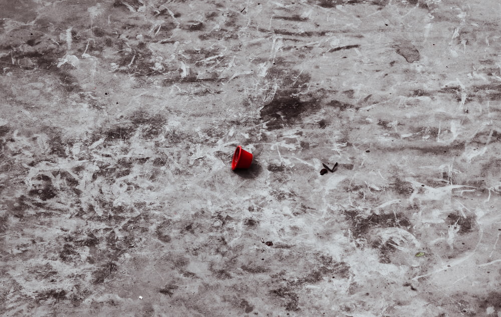 a red umbrella sitting on top of a dirty floor