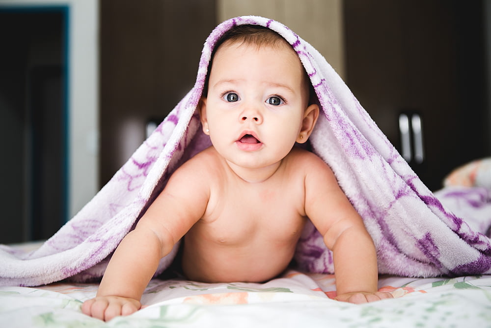 bébé sous couverture violette