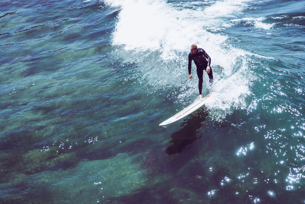 man riding on white surfboard about to surf on ocean waves