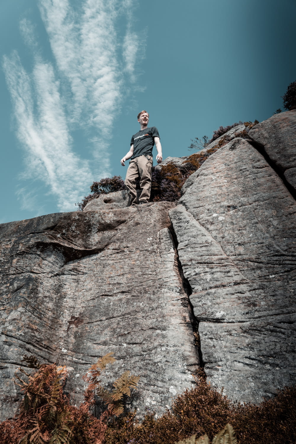 low-angle photography of man standing on a mountain cliff